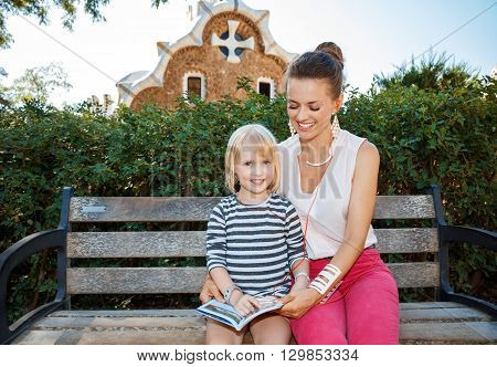Smiling Mother And Daughter Listening Audioguide In Park Guell