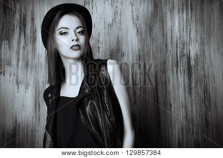 Fashion shot of a modern brunette girl with beautiful big brown eyes wearing black leather jacket and a hat. Beauty, fashion. Youth generation. Black-and-white portrait. 