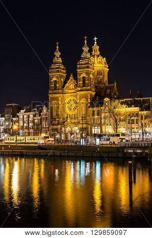 AMSTERDAM NETHERLANDS - 16TH FEBRUARY 2016: A view towards the Church of Saint Nicholas in Amsterdam at night. Reflections can be seen in the water.