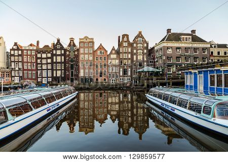 AMSTERDAM NETHERLANDS - 16TH FEBRUARY 2016: Old Buildings along the Damrak in Amsterdam during the day. Boats can be seen.