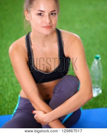 Beautiful young woman relaxing after exerscises on the grass