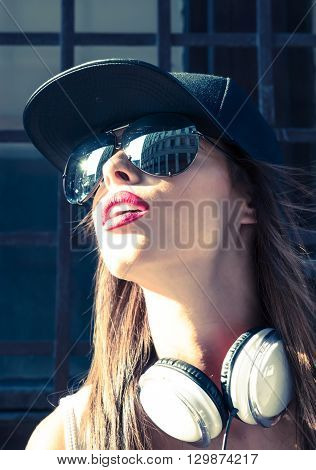 A beautiful young Hip Hop Rapper girl with Headphones in a urban environment.