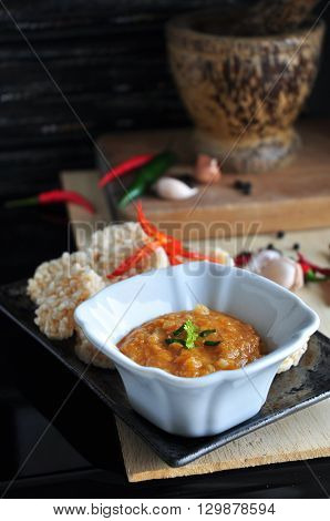 Thai food rice cracker and spicy dip sauce with ingredients and mortar on background