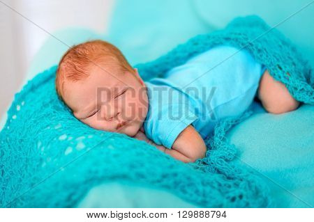 baby sleeping on the tummy on a blue blanket