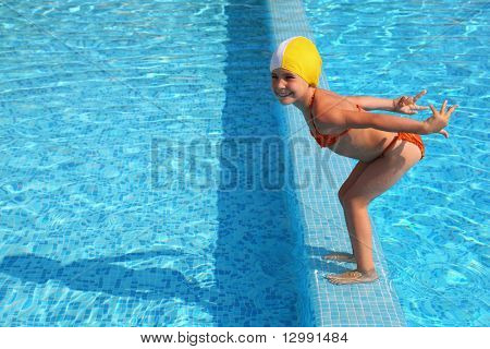Mädchen steht auf Sockelleisten im Pool und bereitet in Wasser springen