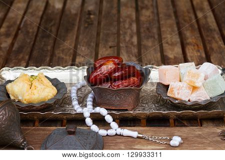 Turkish delights with tasbih on silver oriental tray, copy space on wooden table