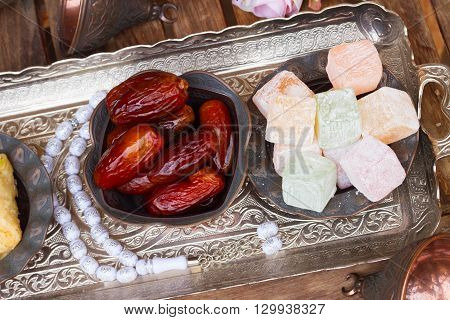 Turkish delights and date fruits with tasbih on silver oriental tray, top view