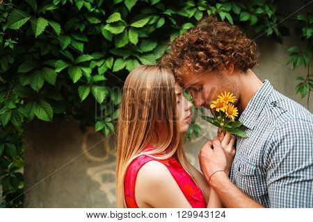 The curly-haired guy with the red-haired girl with freckles on the background of fabulous scenery of city and nature. Lovely couple of lovers on a walk in the city and nature. Tenderness emotion