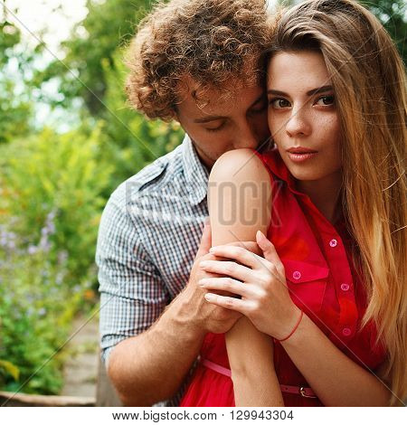 The curly-haired guy with the red-haired girl with freckles on the background of fabulous scenery of city and nature. Lovely couple of lovers on a walk in the city and nature. Tenderness emotion