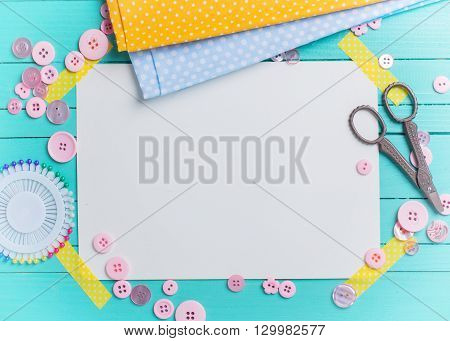 Sewing thread - buttons scissors fabric and empty tag on turquoise wooden background. Selective focus. Scrapbboking. Flat lay. Place for text. Toned image.