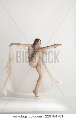 Young Beautiful Dancer In Beige Swimsuit Dancing On Gray Studio Background. Front View. Young Female