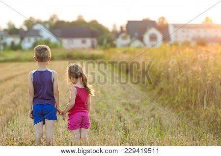 Little Girl And Boy Standind On Field With Golden Sunlight