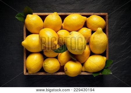 Fresh Lemons In A Wooden Container On A Black Stone Background, Top View