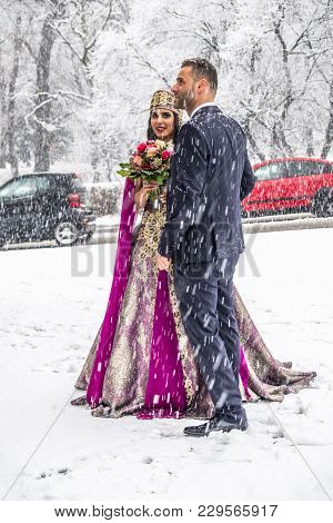 Happy Couple In Traditional Turkish Wedding Dress During Their Wedding In A Snow Storm