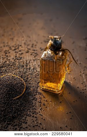 Close Up Of Brown Mustard Seed,with Its Extracted Oil On A Brown Wooden Surface In Dark Gothic Color