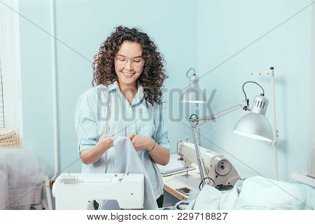 Cheerful Tailor Looking At Blue Fabric In Her Arms At Work