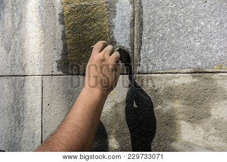 Man With The Help Of A Wet Brush Erases The Graffiti Painted On The Wall. Preparation Of The Surface