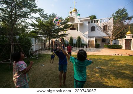 KOH CHANG, THAILAND - FEB 25, 2018: Thai children play in ball near the Russian Orthodox Church. There are currently 10 Orthodox parishes in Thailand, Orthodoxy is practiced by 0.002% of population.
