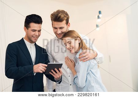 Young Couple In A Meeting With A Realtor. A Guy And A Girl Make A Contract With A Realtor About Buyi