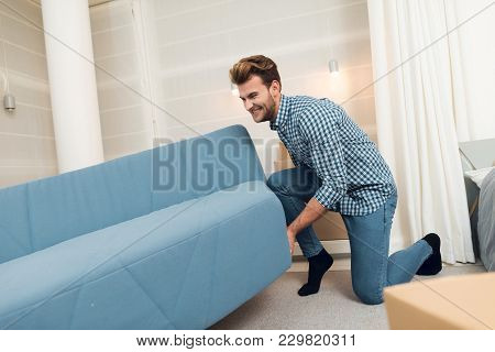 The Guy Moves The Sofa While Moving To A New Home. The Guy Does A Reshuffle In The Room