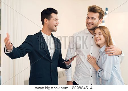 Young Couple In A Meeting With A Realtor. A Guy And A Girl Make A Contract With A Realtor About Buyi