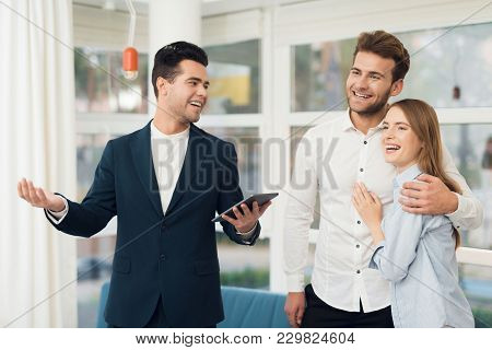 Young Couple In A Meeting With A Realtor. A Guy And A Girl Make A Contract With A Realtor About Buyi