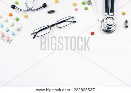 Modern Doctor Desk Table With Stethoscope, Glasses And Pills. Top View With Copy Space, Flat Lay
