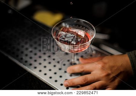 Barman Serving An Adorable Fresh Alcoholic Red Cocktail With An Cooled Ice On The Steel Gray Barstan