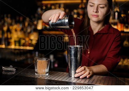 Barmen Girl Putting With A Tongs A Big Ice Cube Into An Empty Glass On The Steel Bar Counter