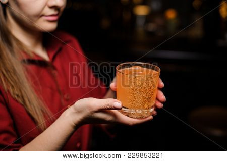 Barmen Girl Putting With A Tongs A Big Ice Cube Into An Empty Glass On The Steel Bar Counter