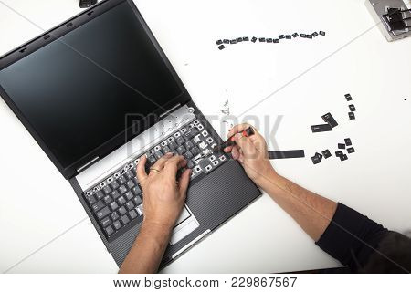 Technician Lifting The Lettering Off The Keys On The Keypad Of An Open Laptop Computer In A Repairs 