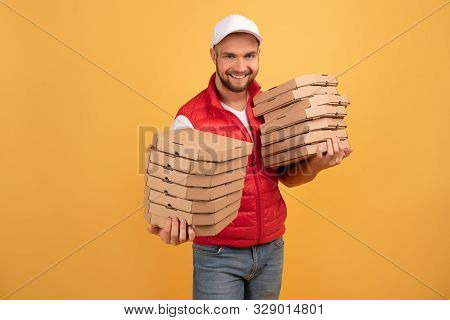 Horizontal Shot Of Happy Man Holds Two Piles Of Carton Boxes With Pizza, Has Surprised Joyful Expres