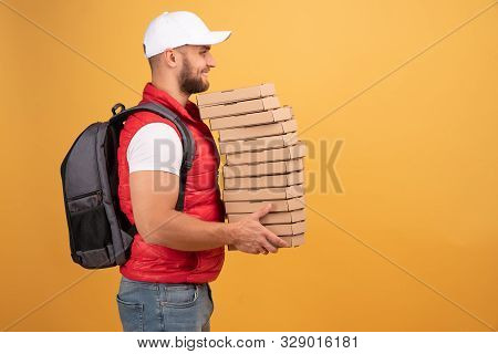 Cheerful Pizza Delivery Man Stands In Profile With Carton Boxes, Waits For Client, Wears White Cap A
