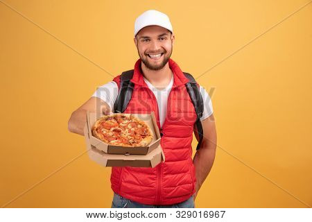 Cheerful Pizza Delivery Man Stands With Carton Box With Pizza, Waits For Client, Wears White Cap And