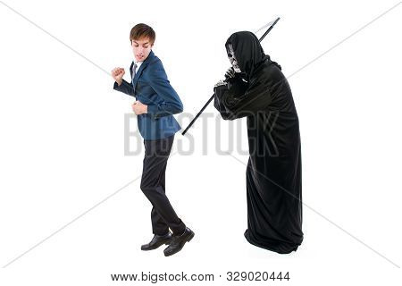Man In A Halloween Grim Reaper Ghost Costume Chasing, Mocking And Making Fun Of Scared Businessman R