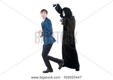 Man In A Halloween Grim Reaper Ghost Costume Chasing, Mocking And Making Fun Of Scared Businessman R