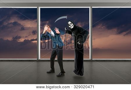 Man In A Halloween Grim Reaper Ghost Costume Chasing, Mocking And Making Fun Of Scared Businessman R