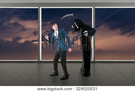 Man In A Halloween Grim Reaper Ghost Costume Chasing, Mocking And Making Fun Of Scared Businessman R