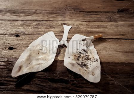 Conceptual Image Of Cigarette Burning On Paper Lungs Isolated On Rustic Background. Advertising Styl