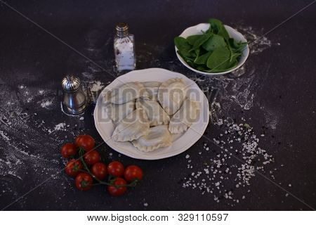 Dumplings. Homemade Dumplings With Stuffing. A Composition Of Dishes With Cherry Tomatoes And Spinac