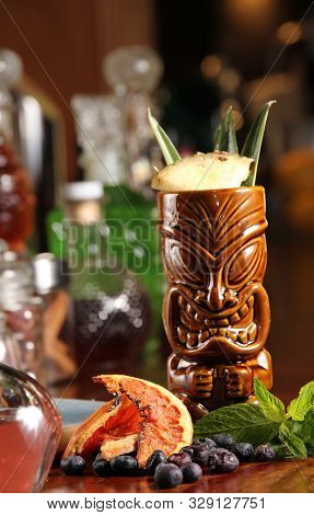 Tiki Cocktail In Tiki Bar With Colorful Background. Dried And Fresh Fruit Tropical Tiki Cocktail Wit