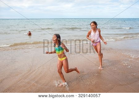 Sisters playing and chasing each other running at the beach