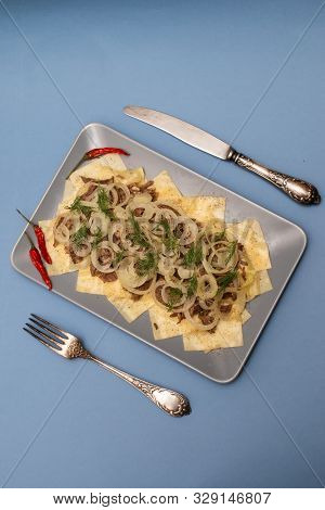 Beshbarmak Is A National Kazakh Dish - Square Pasta With Boiled Meat And Onions. On A Blue Backgroun