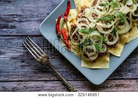 Beshbarmak Is A National Tatar Dish - Square Pasta With Boiled Meat And Onions. On A Black Backgroun