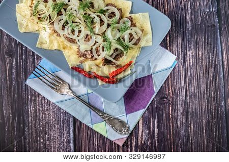 Beshbarmak Is A National Kazakh Dish - Square Pasta With Boiled Meat And Onions. On Wooden Backgroun