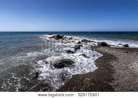 Sea Surf On The Beach With Black Volkanic Sand And Stones.