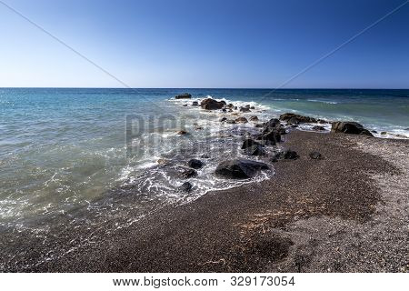 Sea Surf On The Beach With Black Volkanic Sand And Stones.