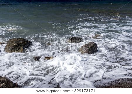 Sea Surf On The Beach With Black Volkanic Sand And Stones.