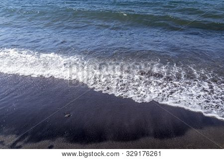 Sea Surf On The Beach With Black Volkanic Sand.