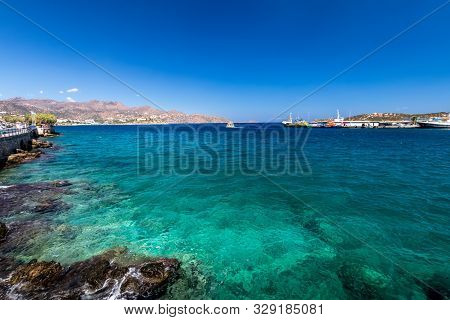 Agios Nikolaos Coastline On A Sunny Day With Clear Sea And Cliffs.